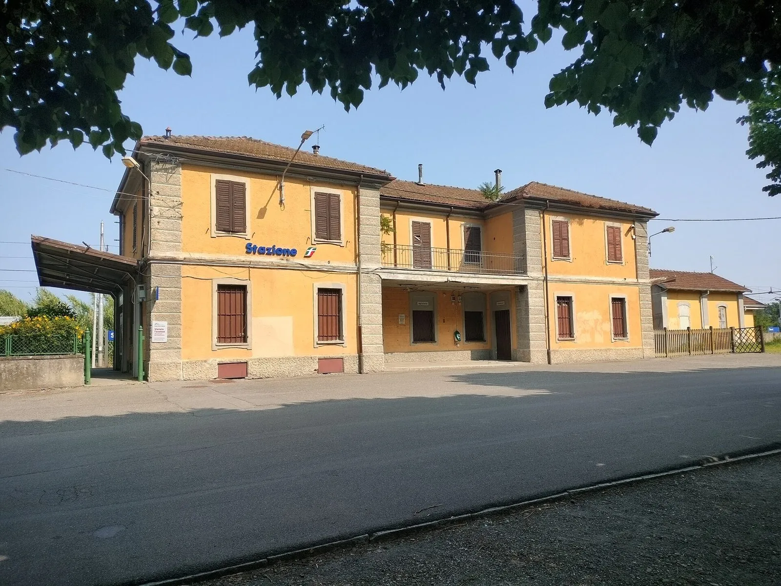 Il fabbricato giallo della stazione ferroviaria di Strevi con le persiane marroni, in una giornata di sole