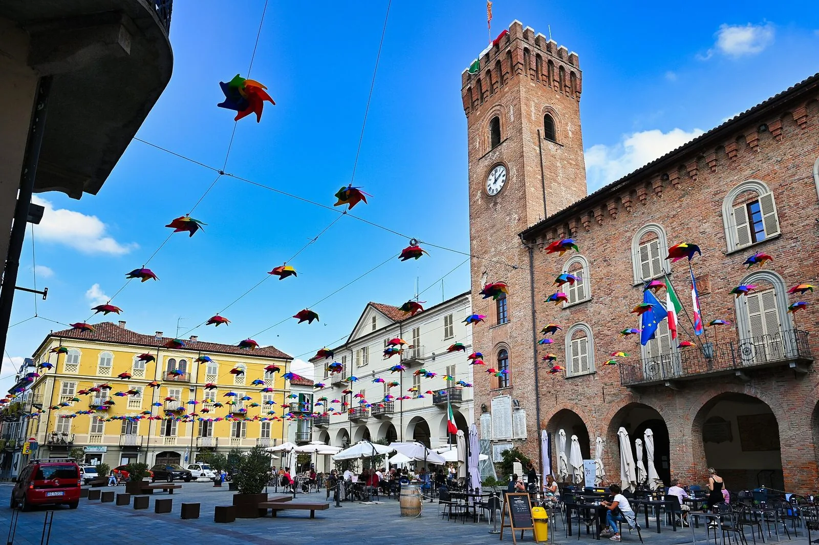 La torre civica del Campanon e il Palazzo Comunale in mattoni di Nizza Monferrato, con la piazza e decorazioni colorate sospese